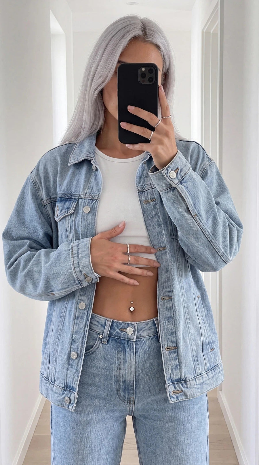 Spegelbild av tjej i jeansjacka med navelpiercing