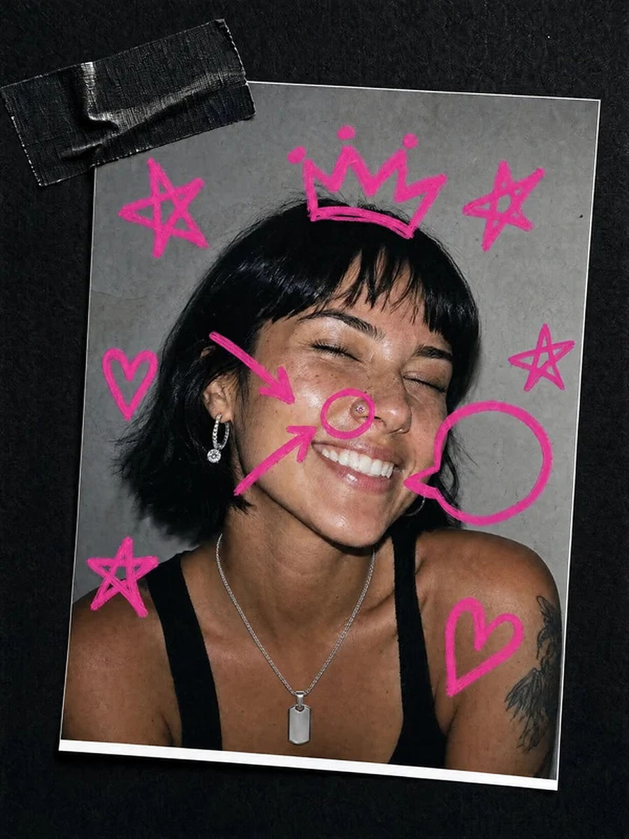Skrattande tjej med näspiercing och rosa klotter runt ansiktet