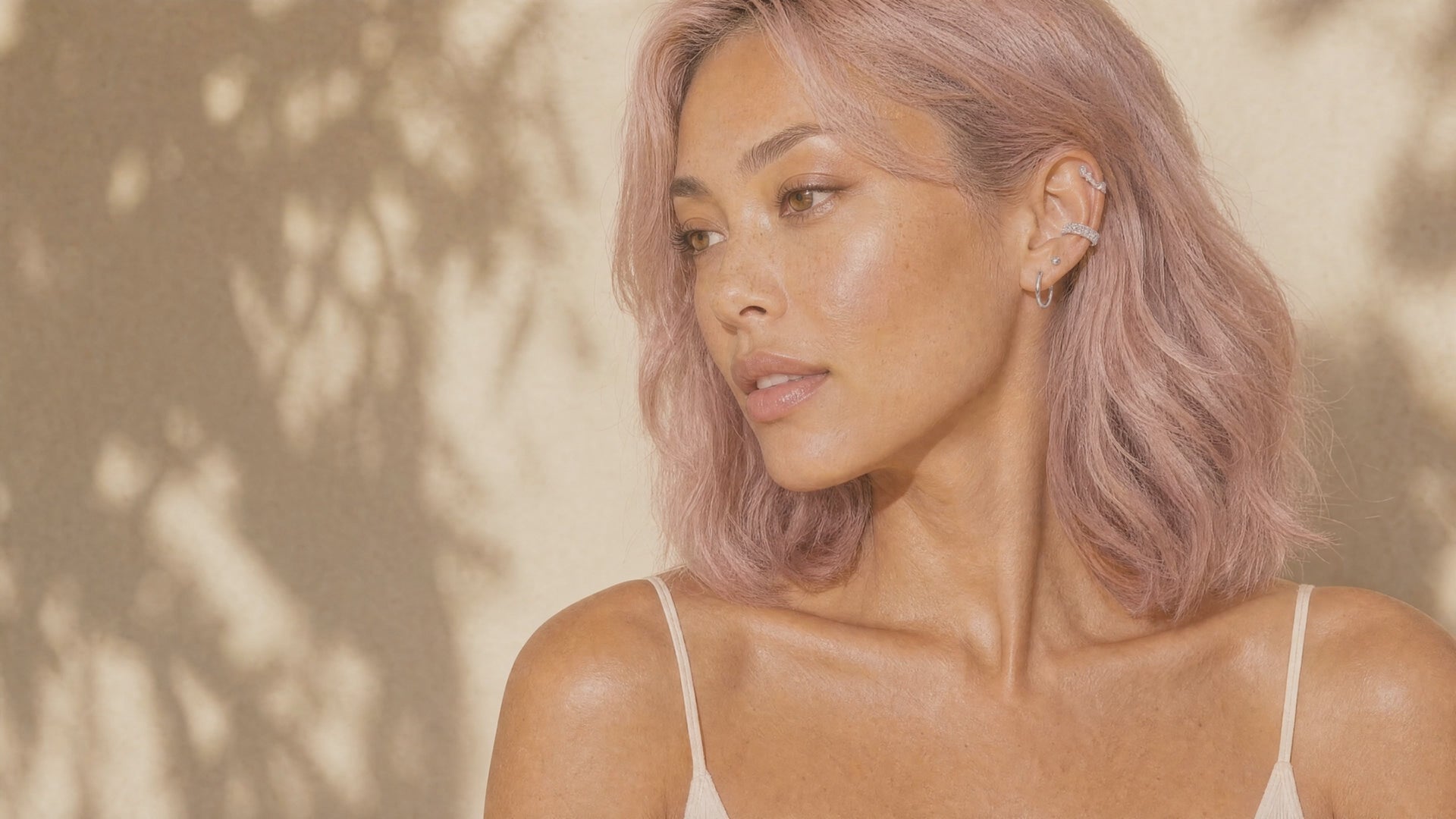 Kvinna i profil med rosa hår och en ear-stack i örat